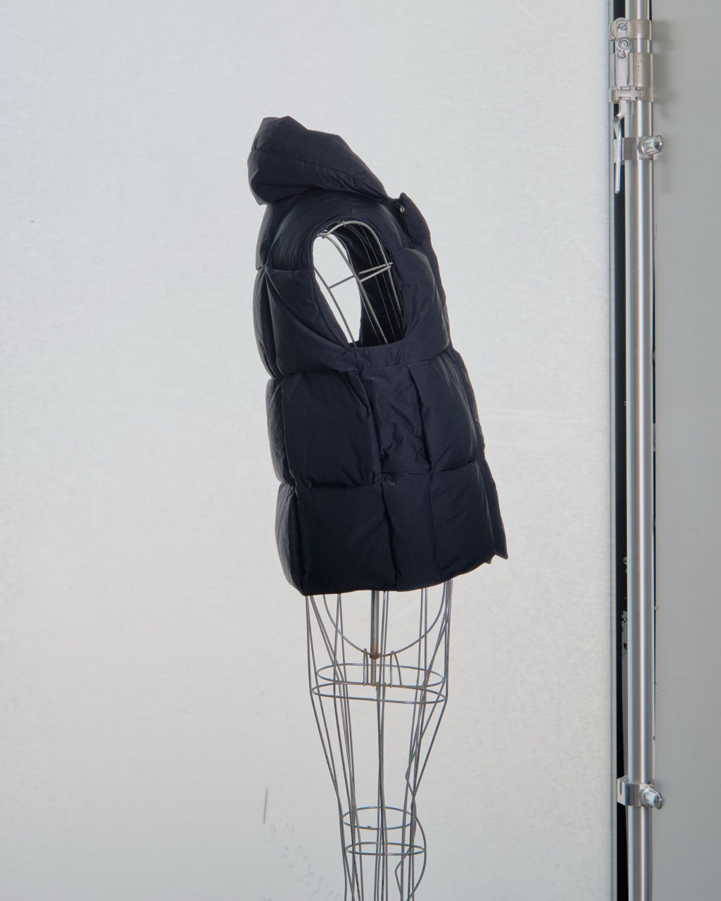 Black Bottega Veneta puffer vest on a mannequin against a white background