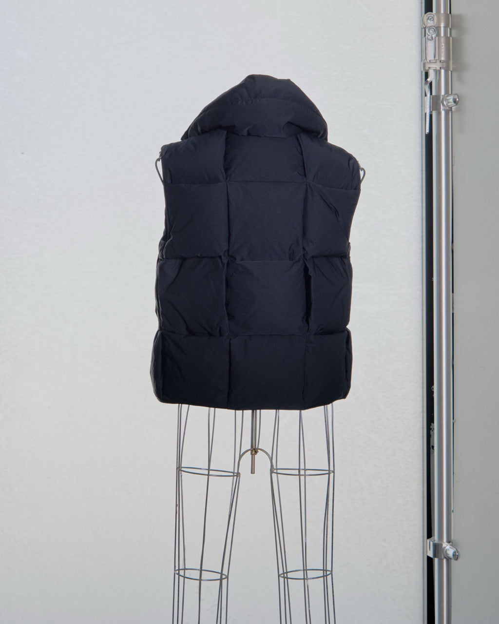 Black Bottega Veneta puffer vest on a mannequin against a white background