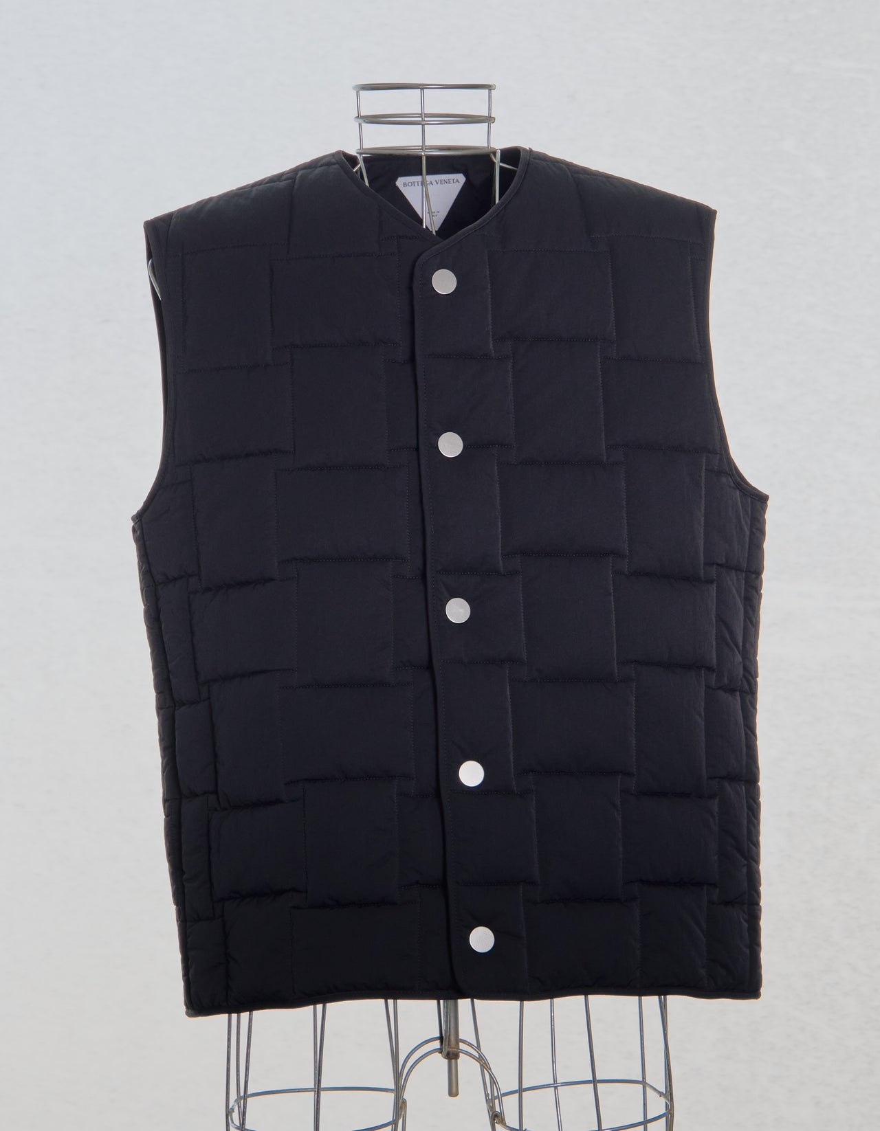 Black Bottega Veneta puffer vest on a mannequin against a light gray background