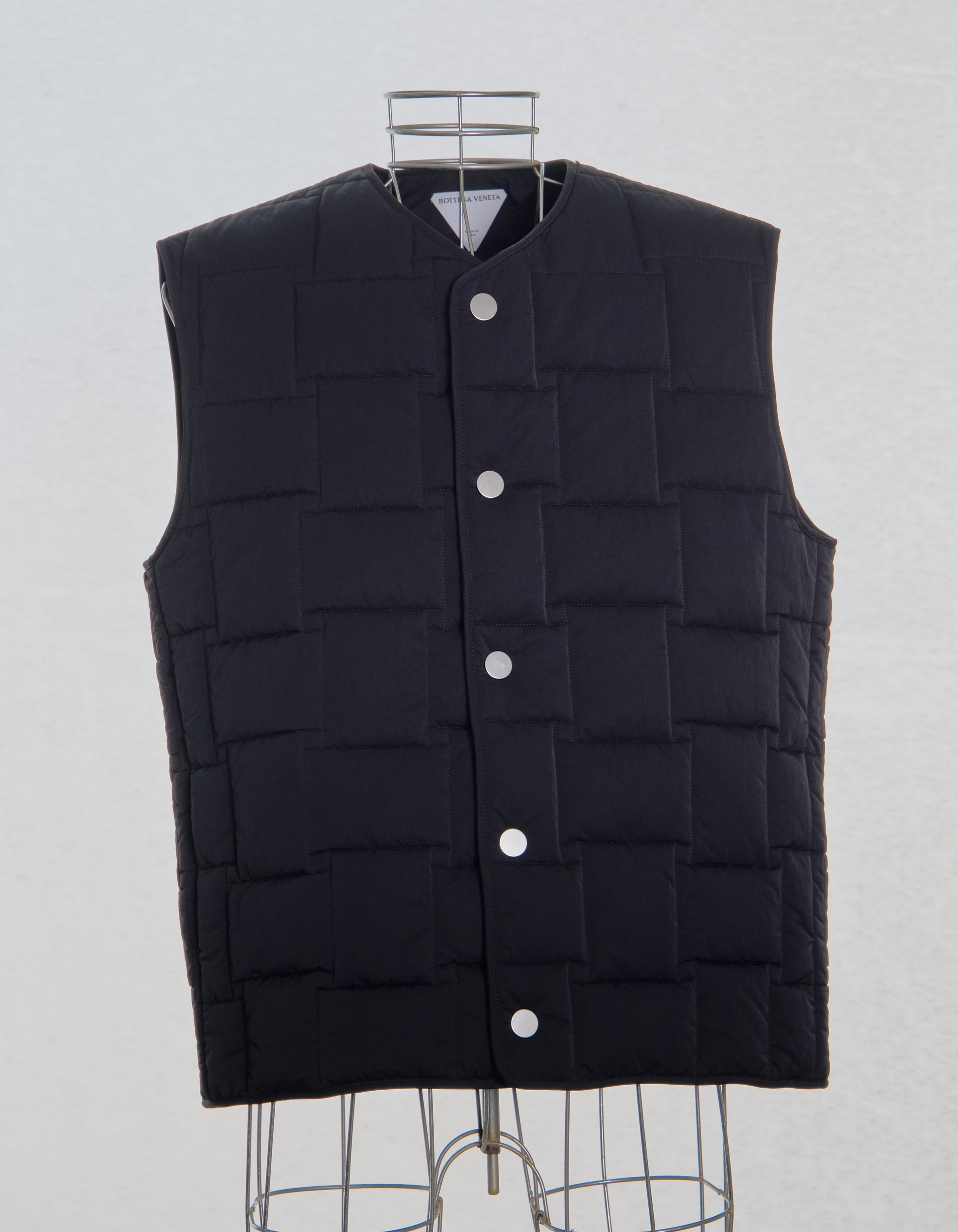 Black Bottega Veneta puffer vest on a mannequin against a light gray background