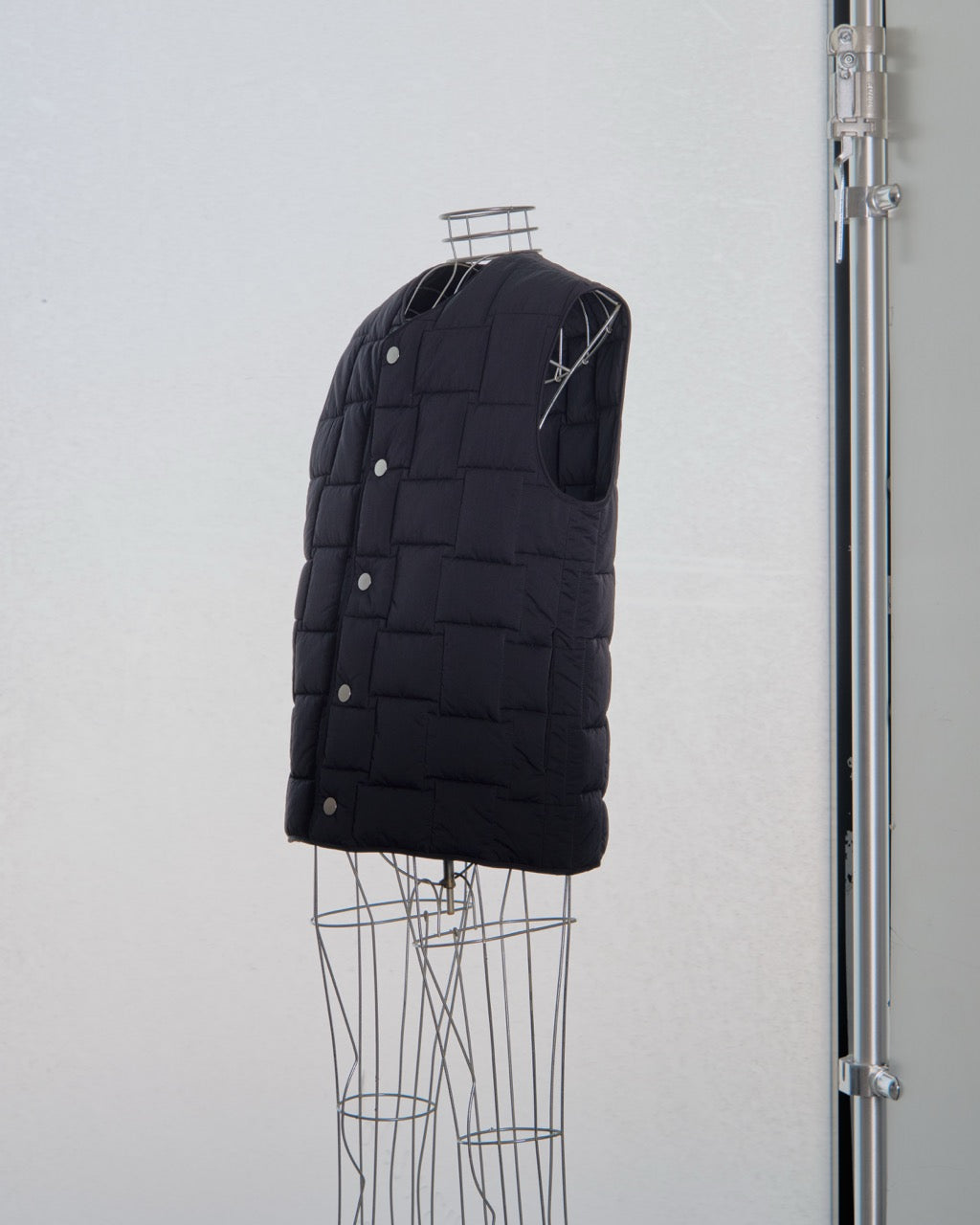 Black Bottega Veneta puffer vest on a mannequin against a light gray background