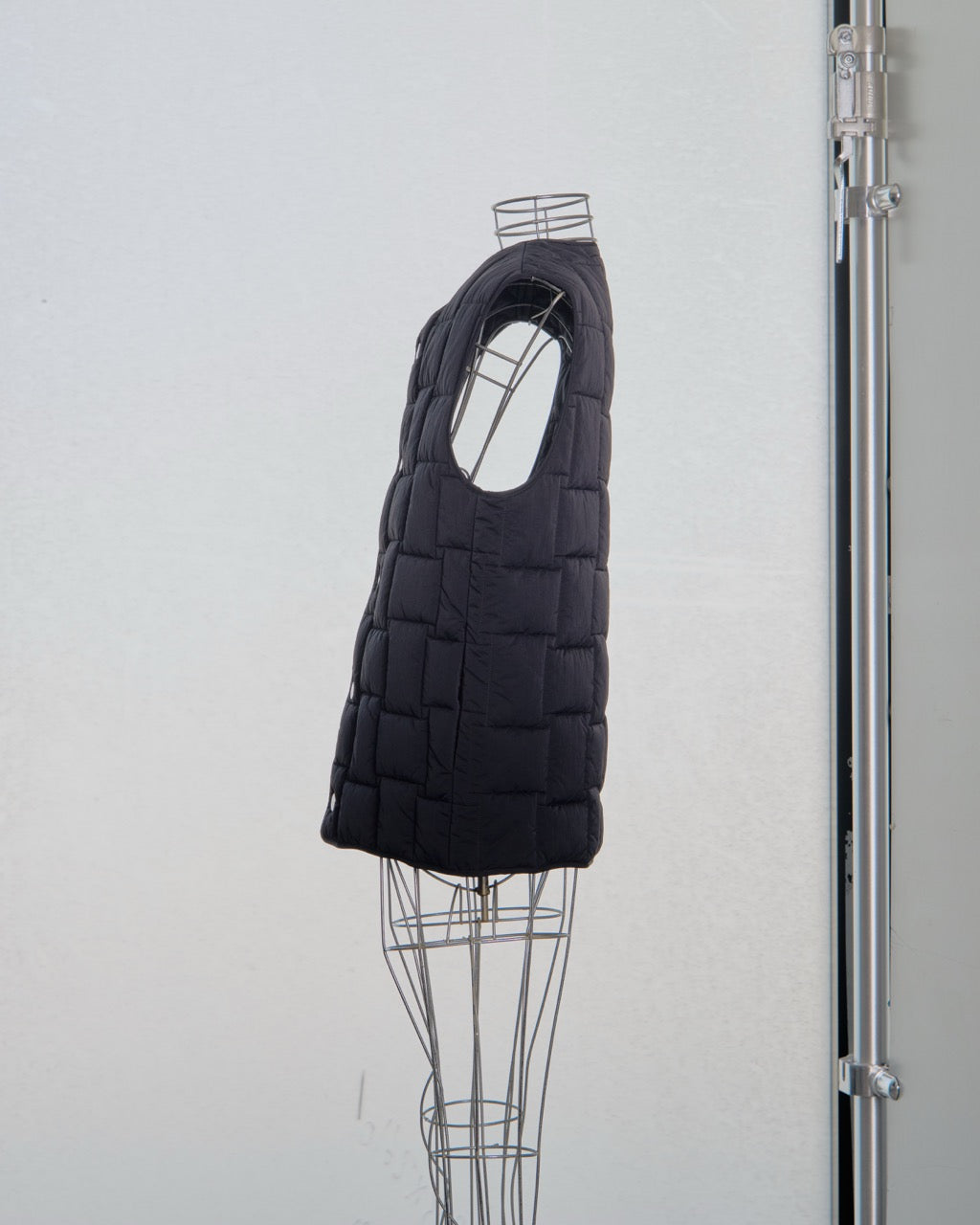 Black Bottega Veneta quilted vest on a mannequin against a white background