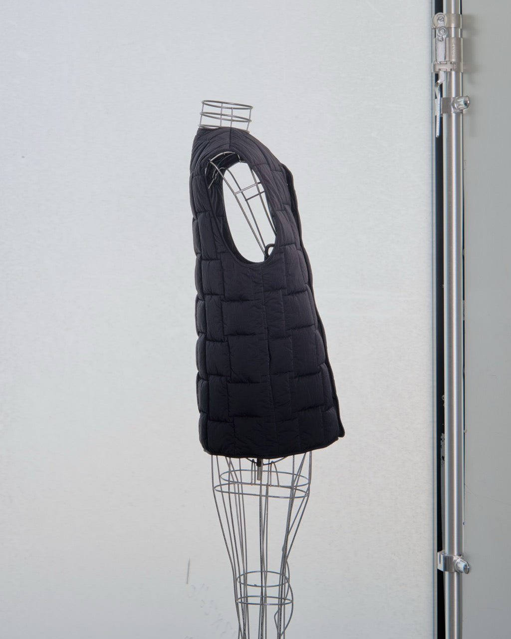 Black Bottega Veneta puffer vest on a mannequin against a white background