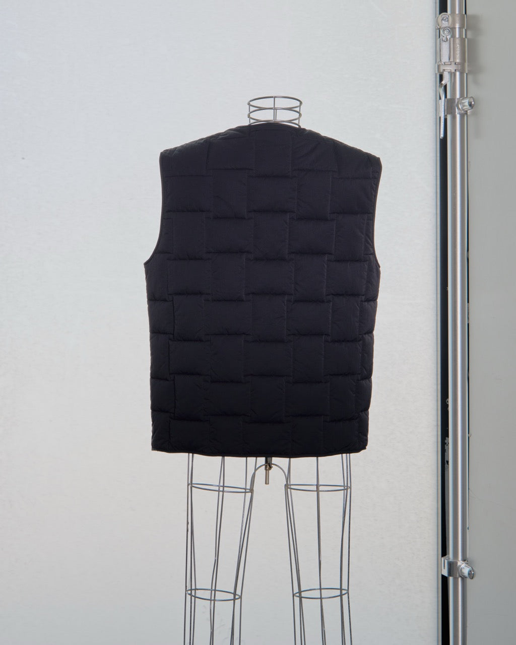 Black Bottega Veneta quilted vest on a mannequin against a white background