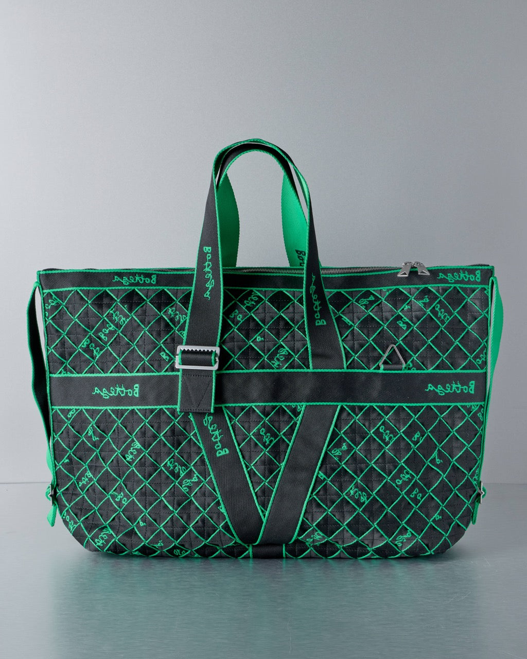 Green and black patterned Bottega Veneta tote bag on a gray background