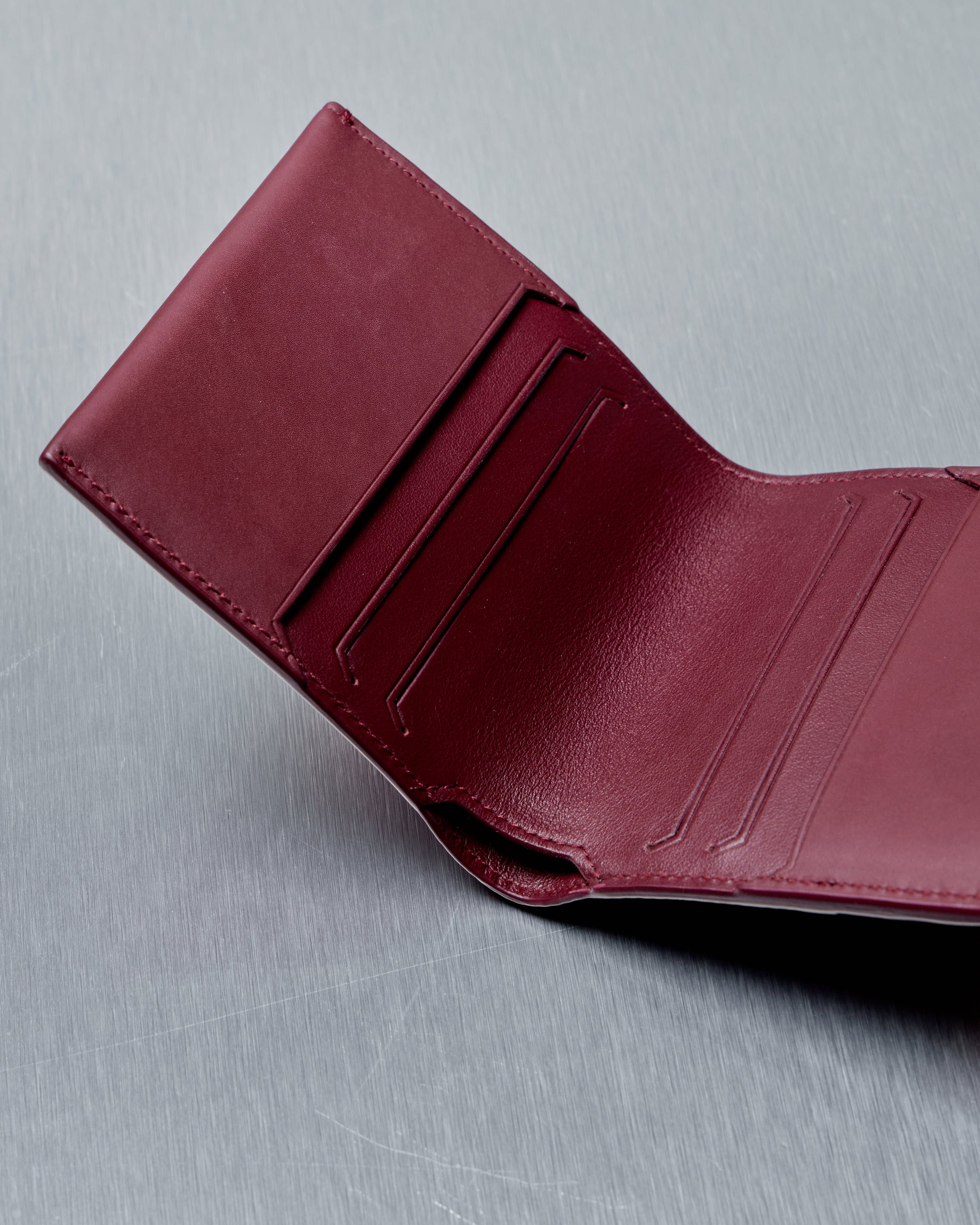 Red leather Bottega Veneta wallet on a gray background