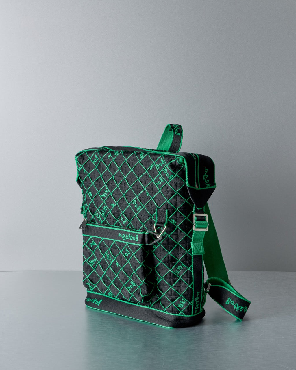 Green and black Bottega Veneta patterned backpack on a gray background