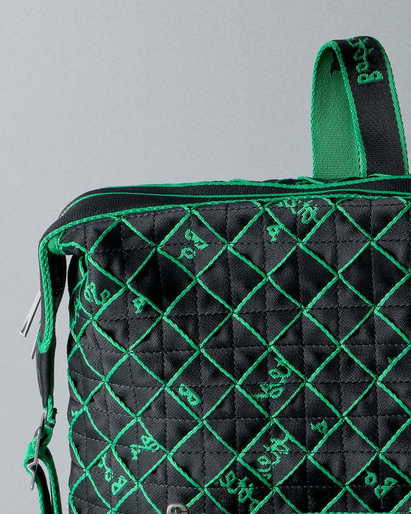 Black quilted Bottega Veneta bag with green stitching on a gray background