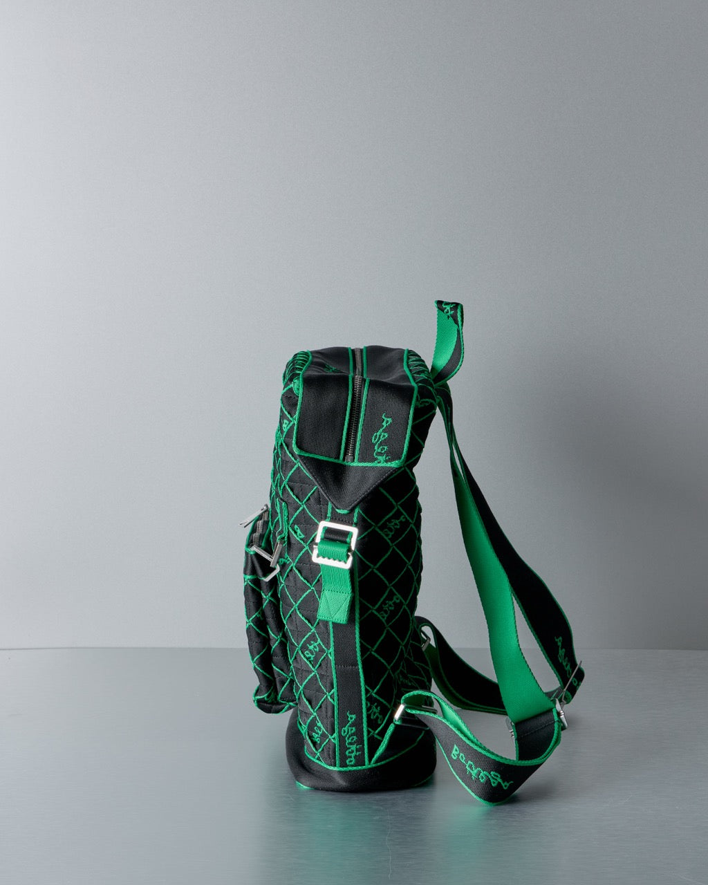Black and green Bottega Veneta bag with a strap on a gray background