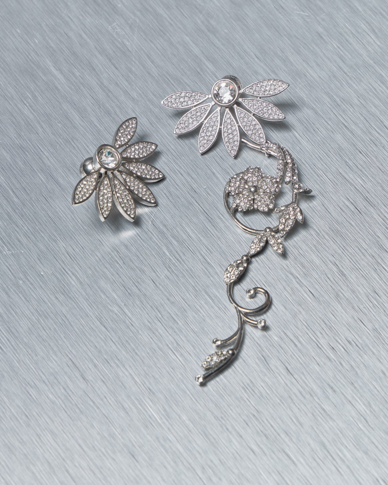 Silver floral Burberry earrings on a textured gray surface