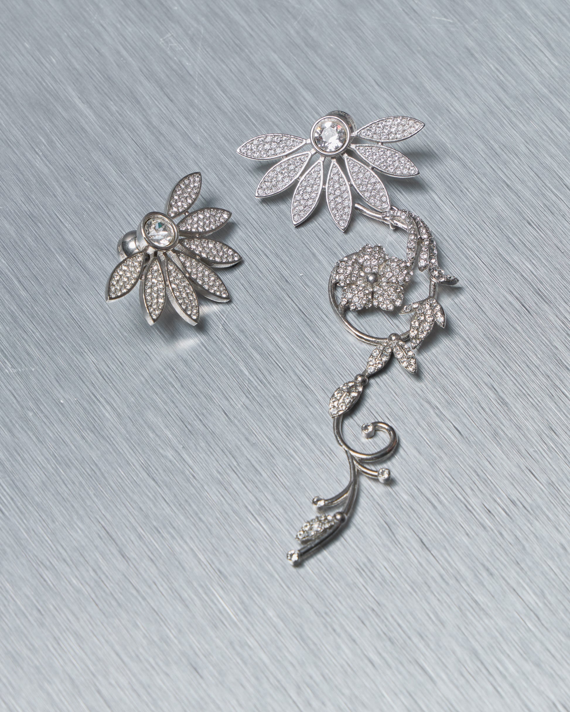 Silver floral Burberry earrings on a textured gray surface