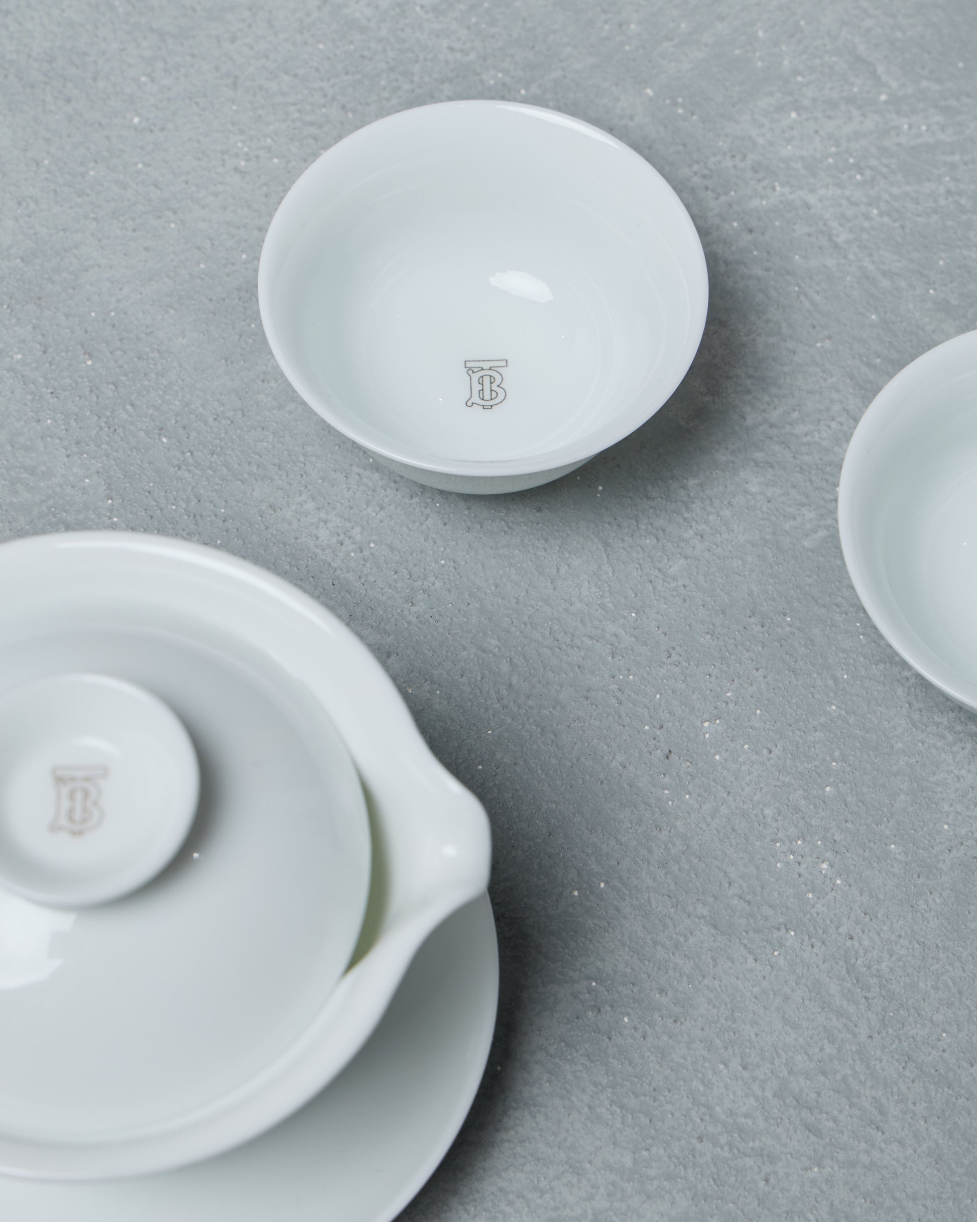 White ceramic Burberry teapot and two cups on a gray surface