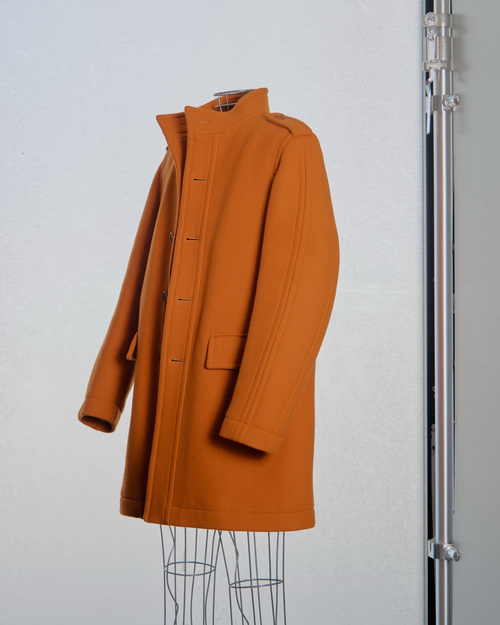 Orange Burberry coat on a mannequin against a light gray background