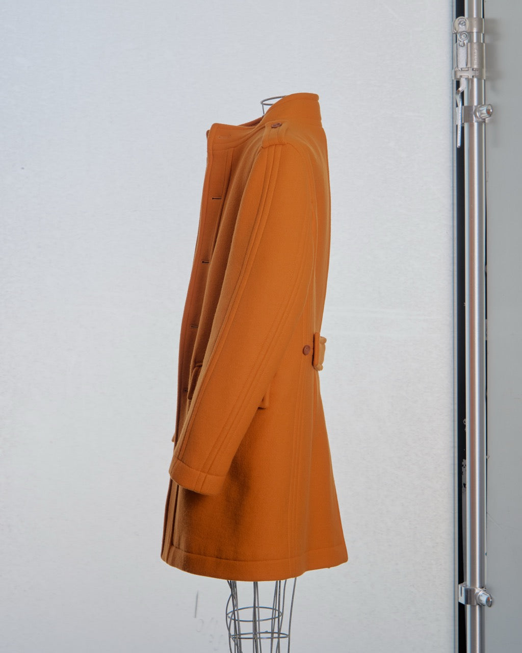 Orange Burberry coat on a mannequin against a white background