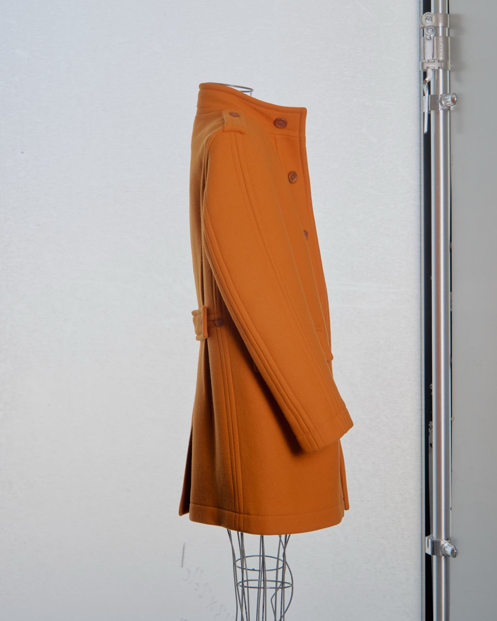 Orange Burberry coat on a mannequin against a white background
