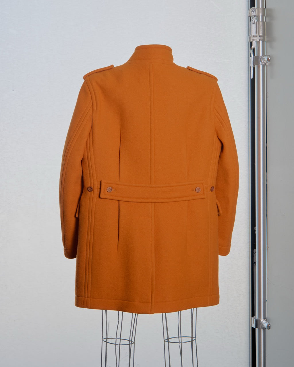 Orange Burberry coat on a mannequin against a plain background