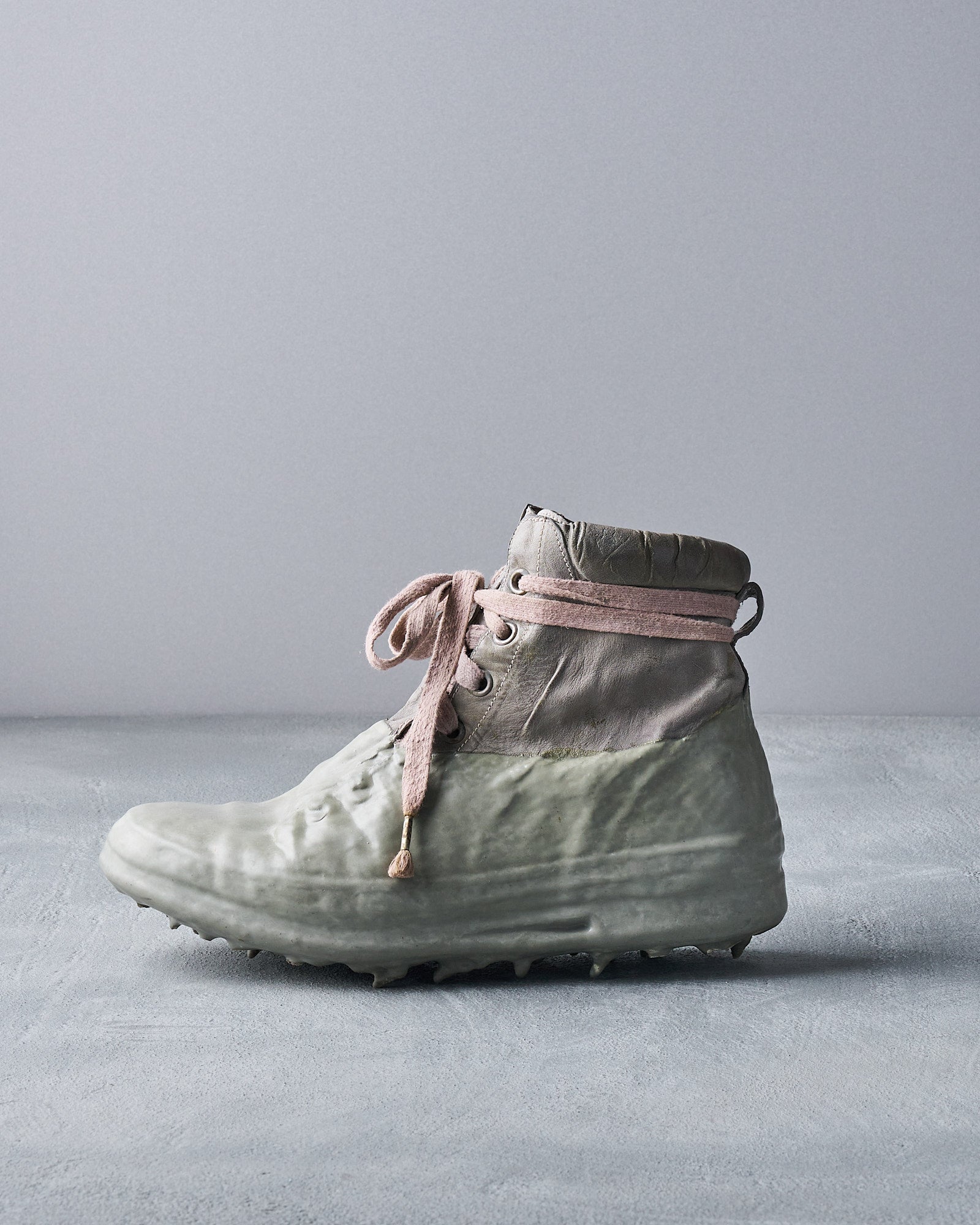 A high-top Carol Christian Poell kangaroo drip sneaker with lace-up closures, oxidised metal hardware, and a padded collar in a neutral color scheme.
