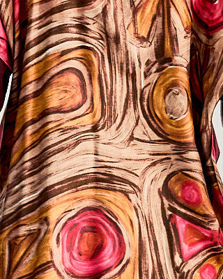 Abstract fabric pattern on a Celine sweater resembling tree rings with swirling brown, orange, and pink hues. 