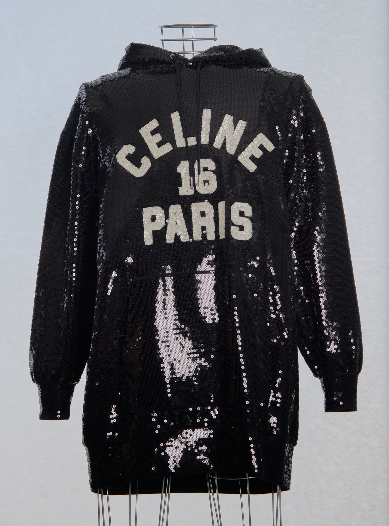 Black sequin hoodie with 'Celine 16 Paris' text on a light blue background