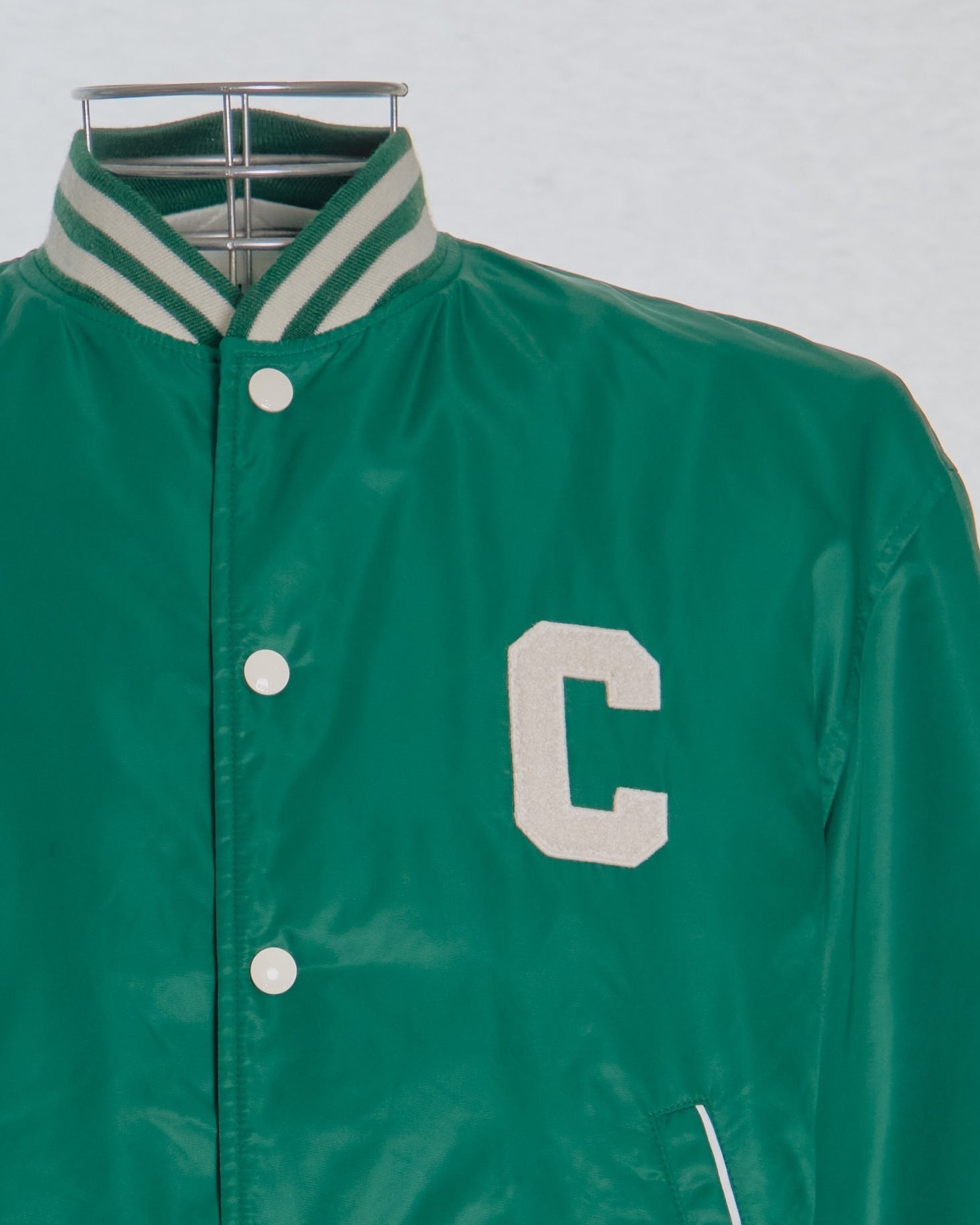 Green Celine varsity jacket with a white 'C' on a gray background
