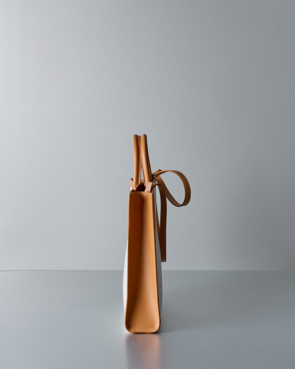 Tan leather Celine handbag with a strap on a gray background