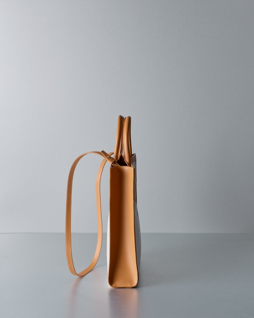 Tan Celine handbag with a strap on a gray background