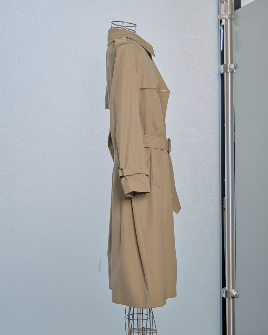 Beige Celine trench coat on a mannequin against a white wall