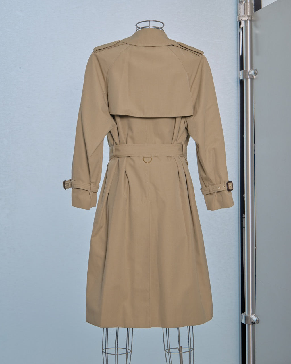 Beige Celine trench coat on a mannequin against a light blue background