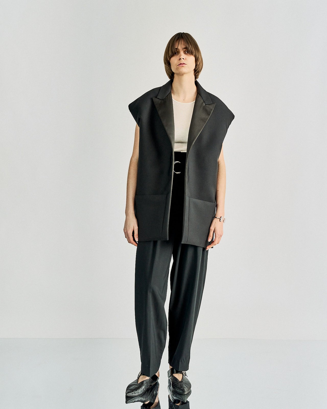 A model wearing Celine high-waist pleated trousers with a belt, featuring a black and white colour scheme.