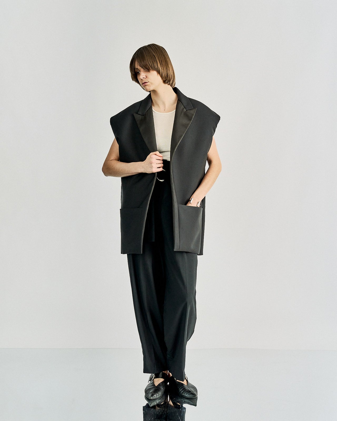 Model walking on a runway wearing a black Celine coat over a white dress.