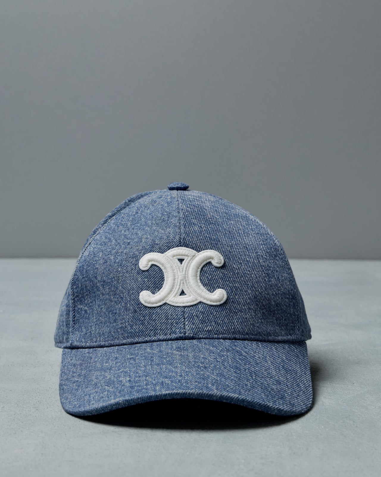 Blue denim Celine cap with a white logo on a gray background