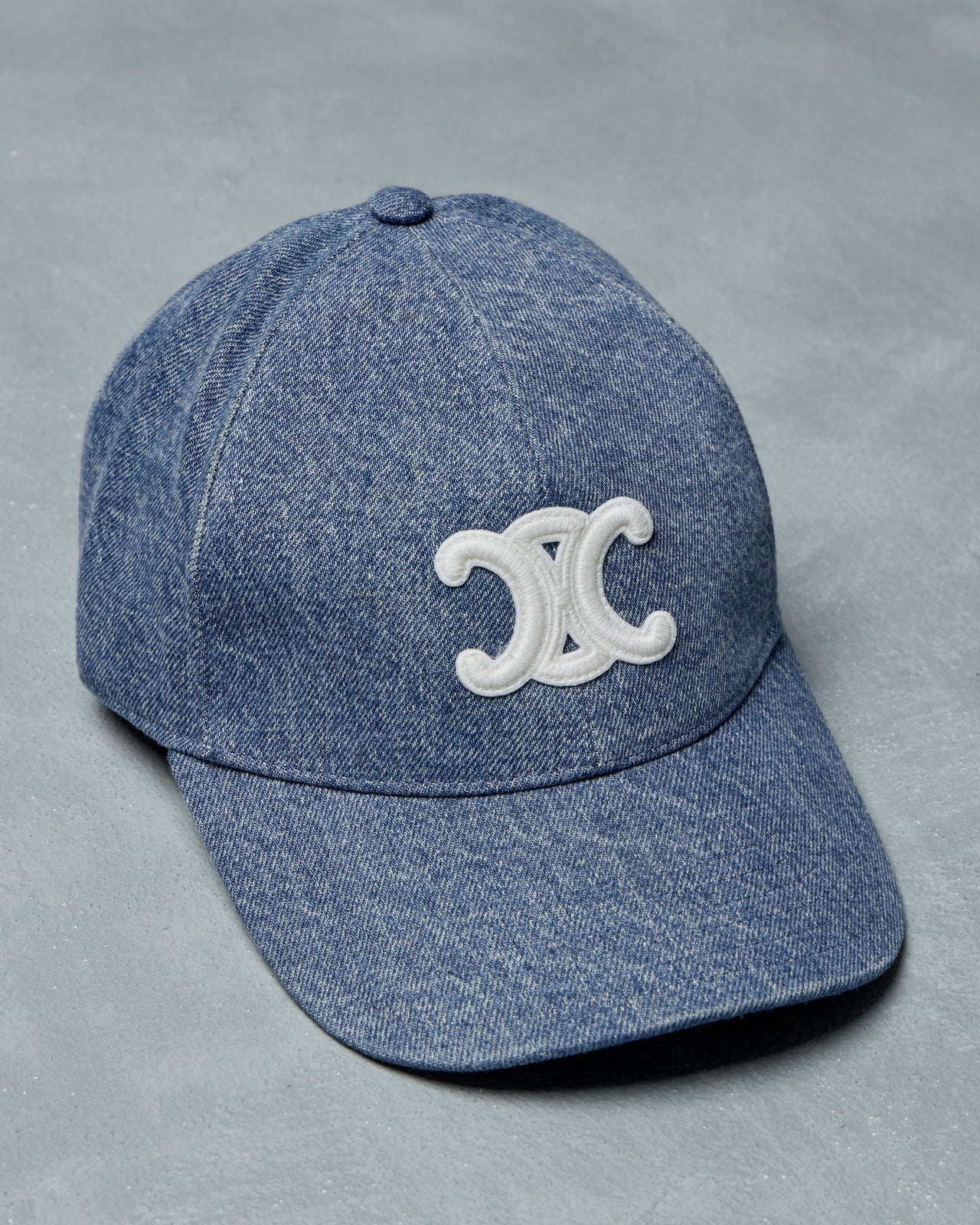 Blue denim Celine cap with a white logo on a gray background