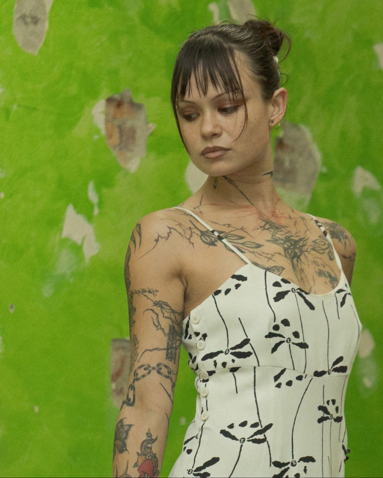 A person standing in a dilapidated room wearing a floral print mini Chanel dress with a hidden back zip and hook closure.