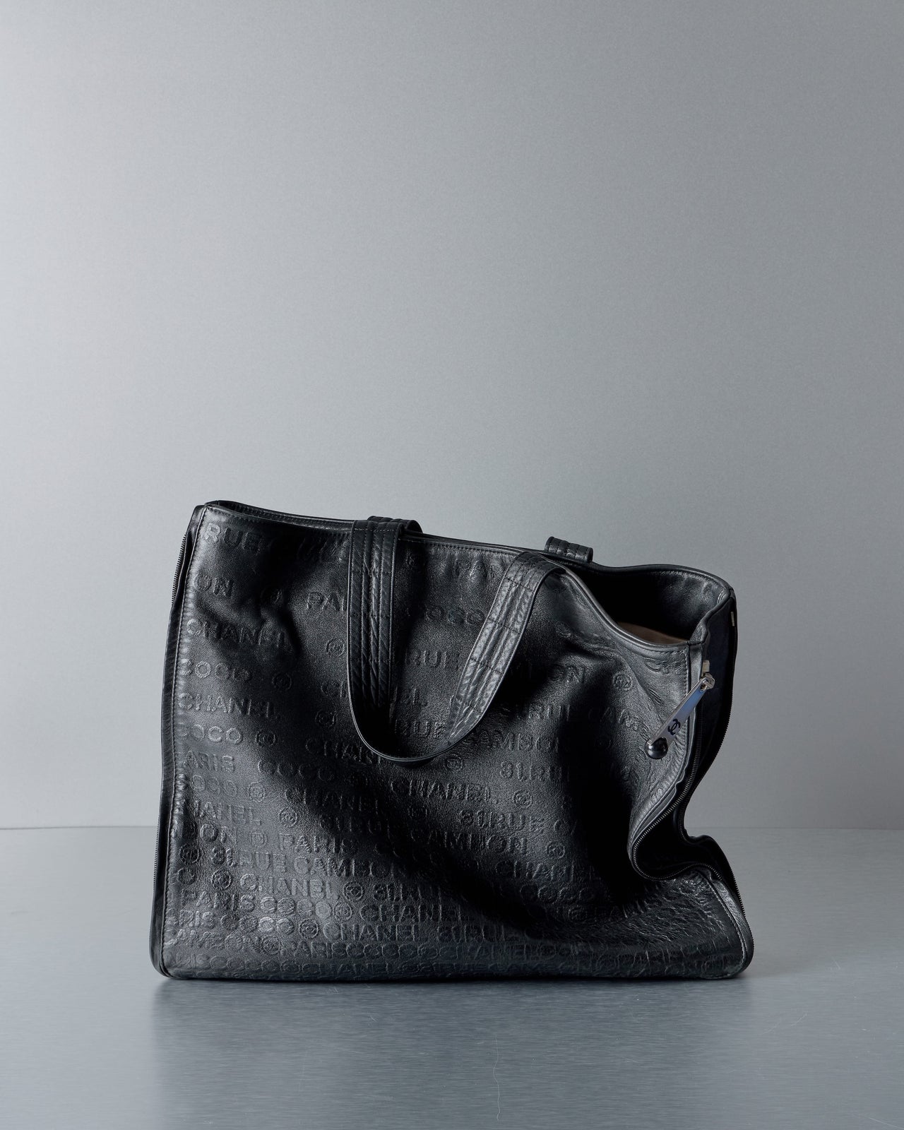 Black textured Chanel tote bag on a gray background