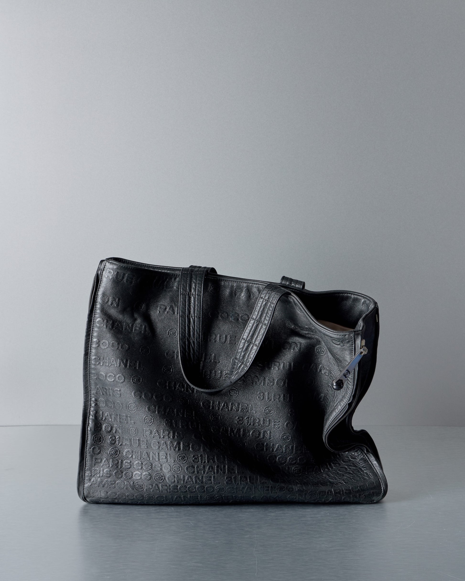Black textured Chanel tote bag on a gray background