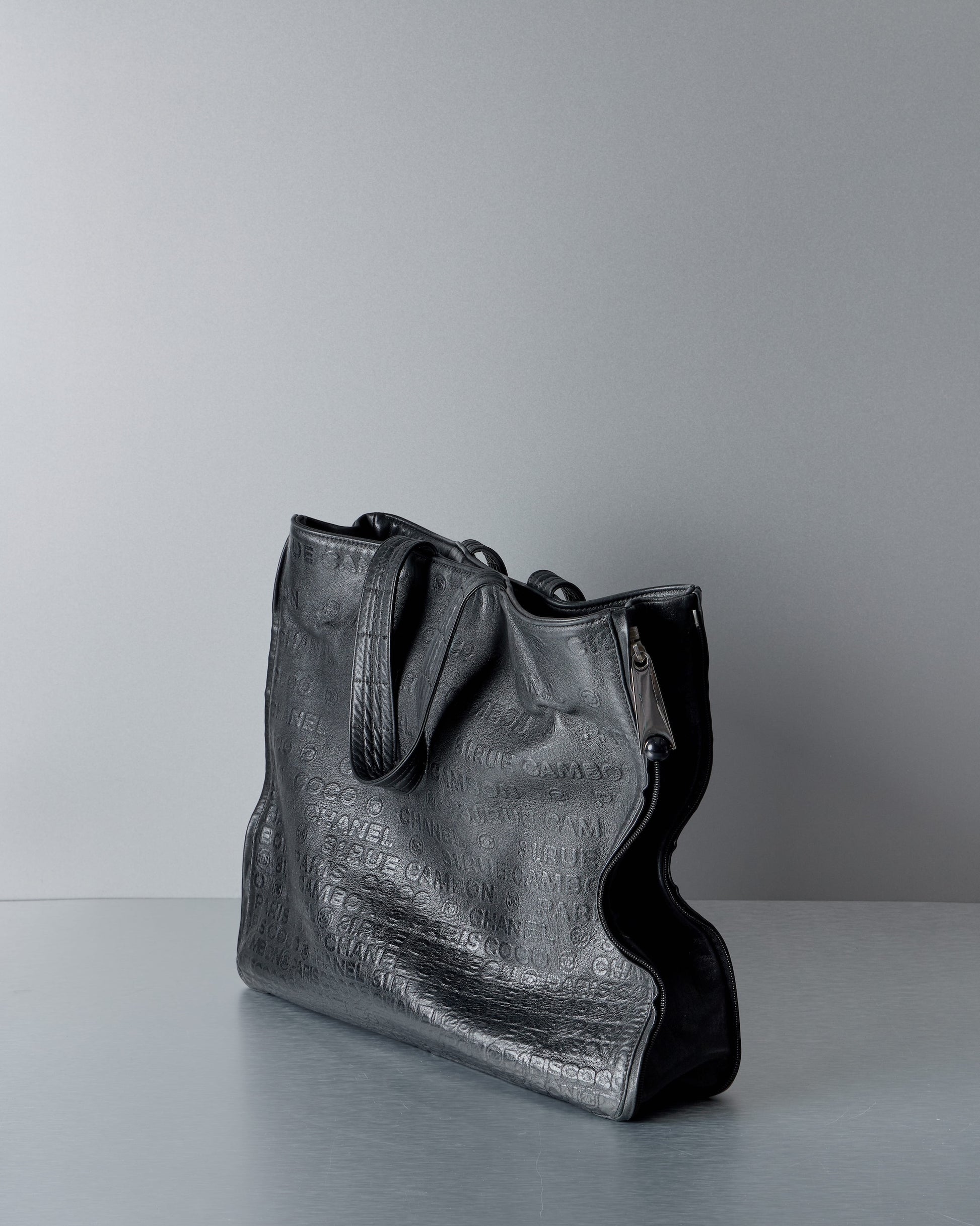 Black leather Chanel handbag on a gray background