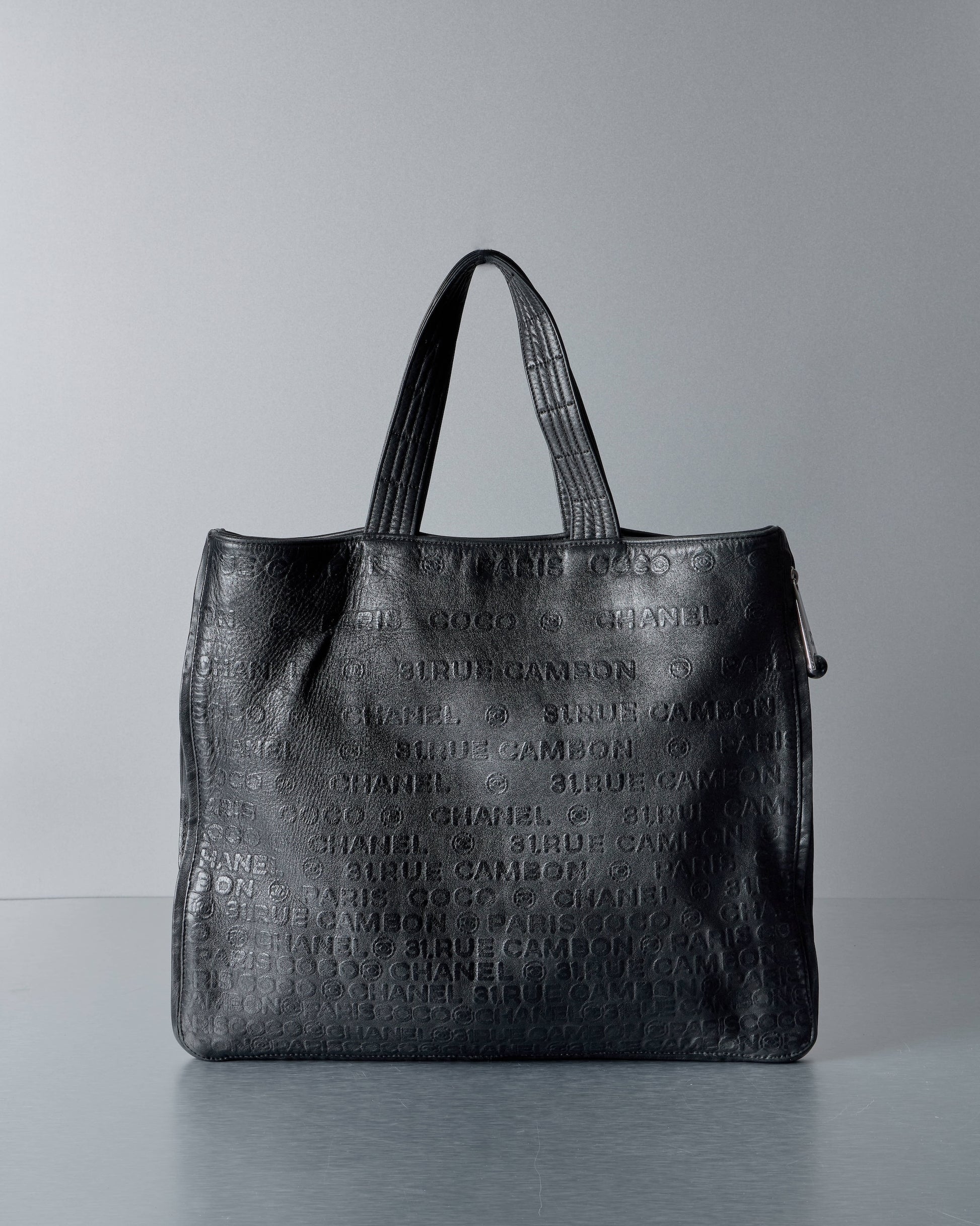 Black textured Chanel handbag on a gray background