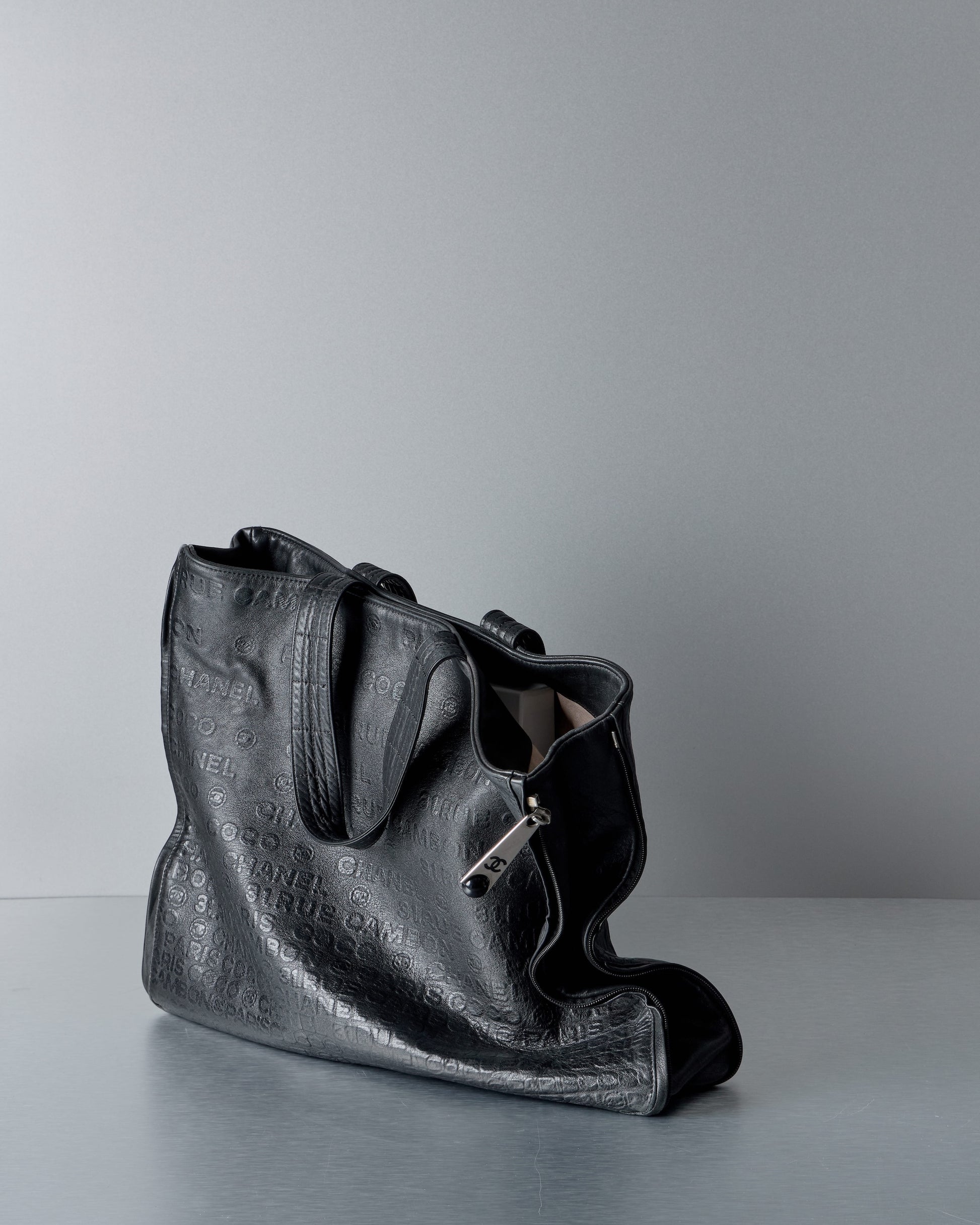 Black leather Chanel handbag on a gray background
