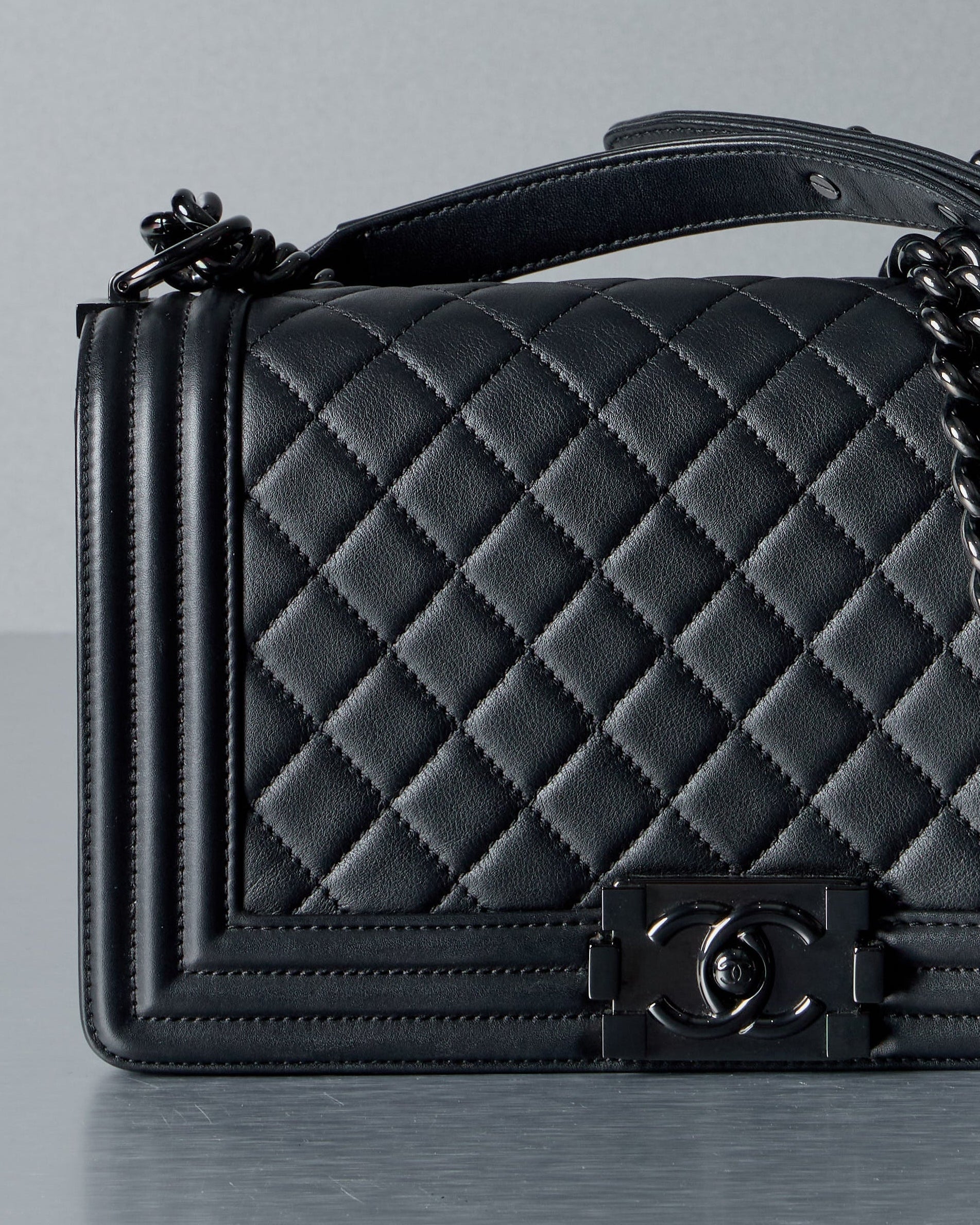 Black quilted handbag with Chanel logo on a gray background