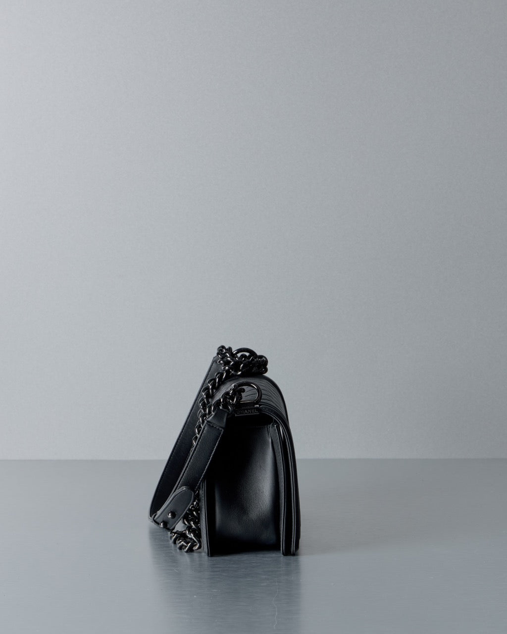 Black Chanel handbag with chain detail on a light gray background