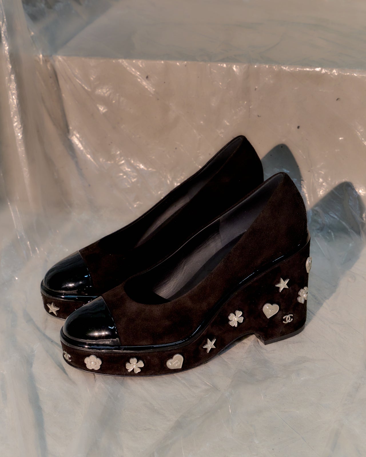 Pair of black high-heeled Chanel shoes with star and clover pattern on a white background