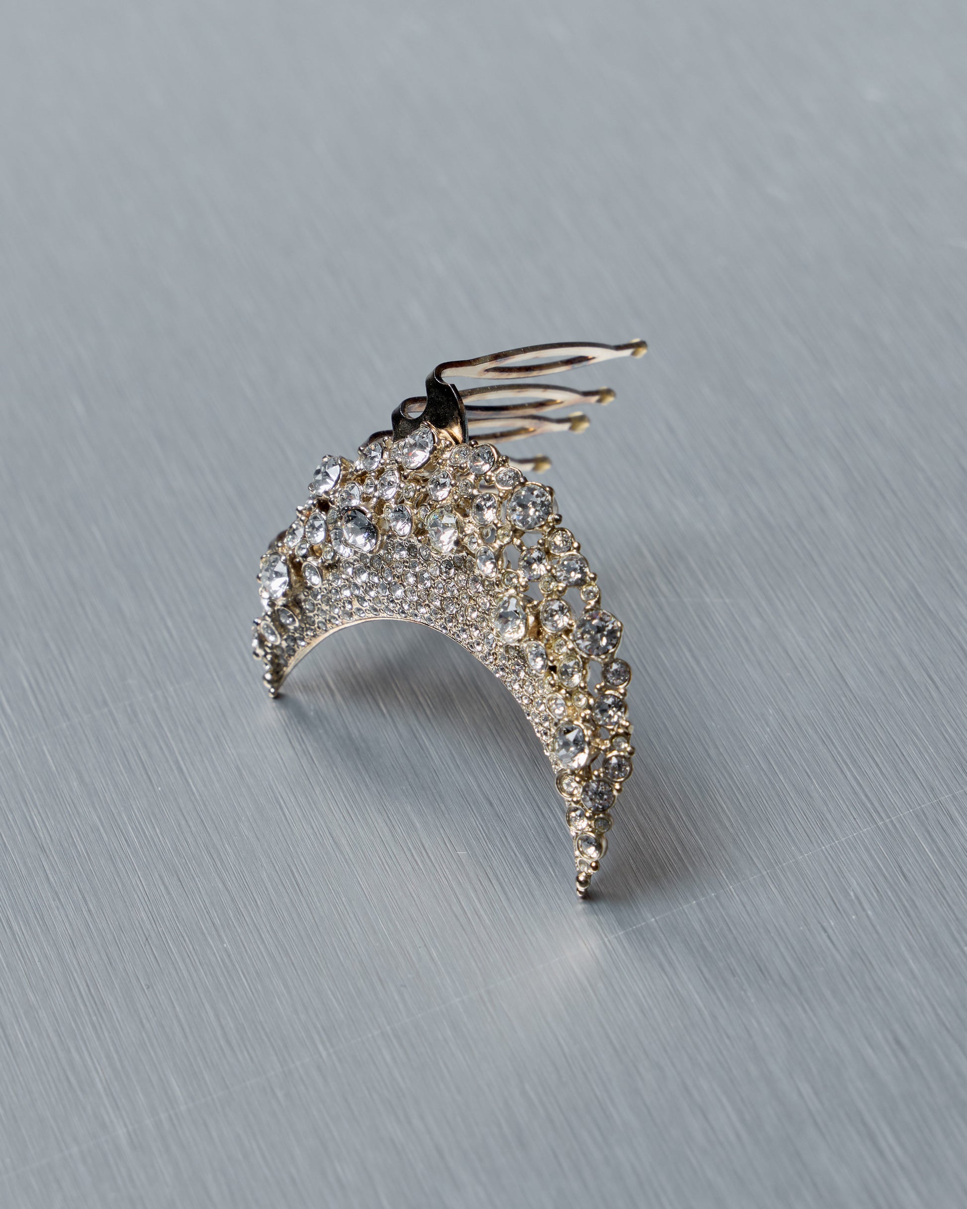 Decorative Chanel half-moon hair clip with crystal details on a gray background