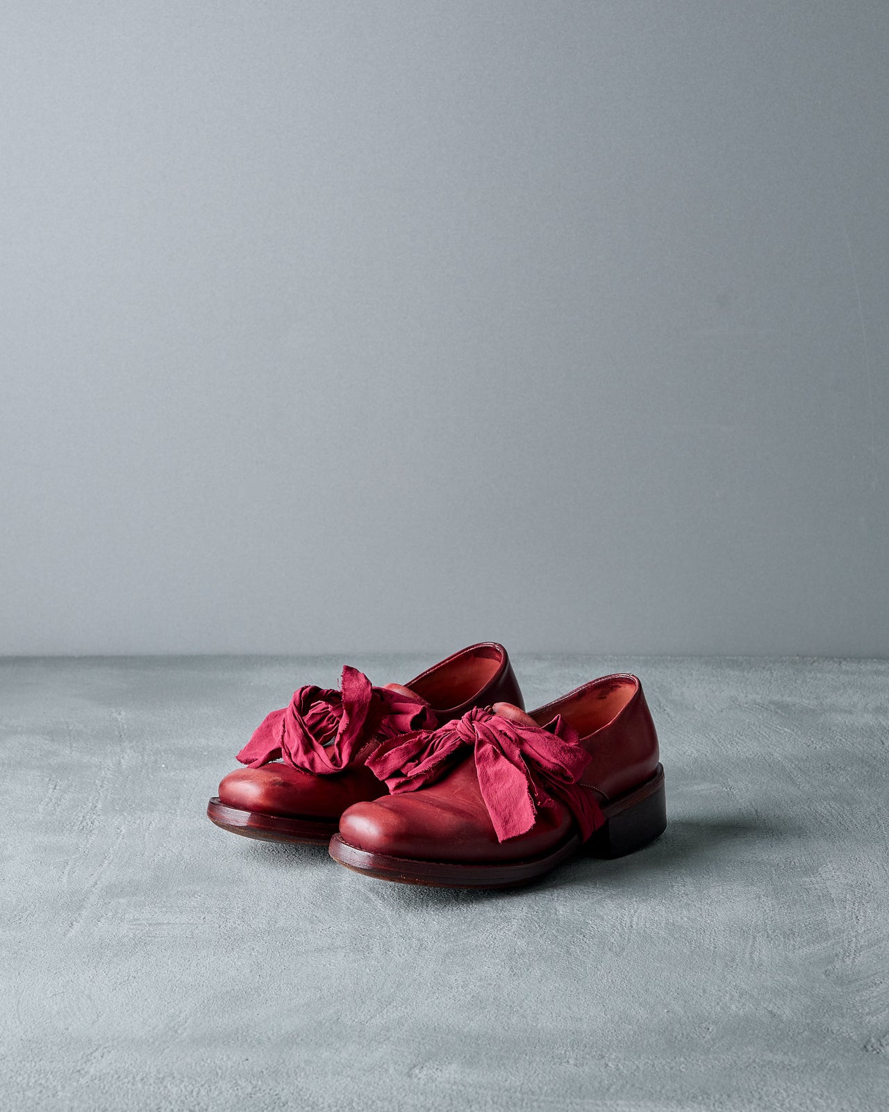 Red Cherevichkiotvichki  shoe with ruffles on a gray background