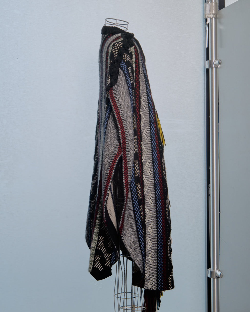 Multicoloured patterned Chloe poncho on a mannequin against a plain background