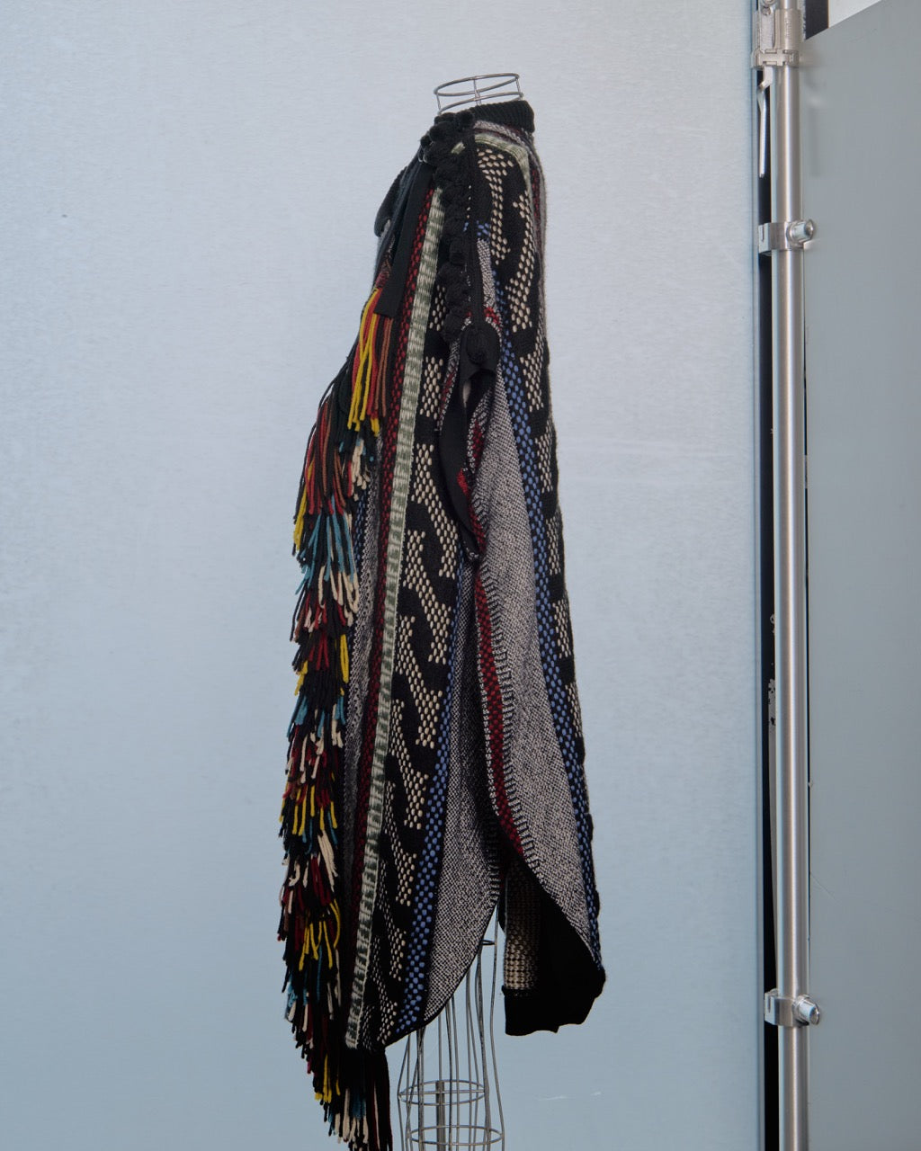 Multicoloured patterned Chloe poncho coat on a mannequin against a light gray background