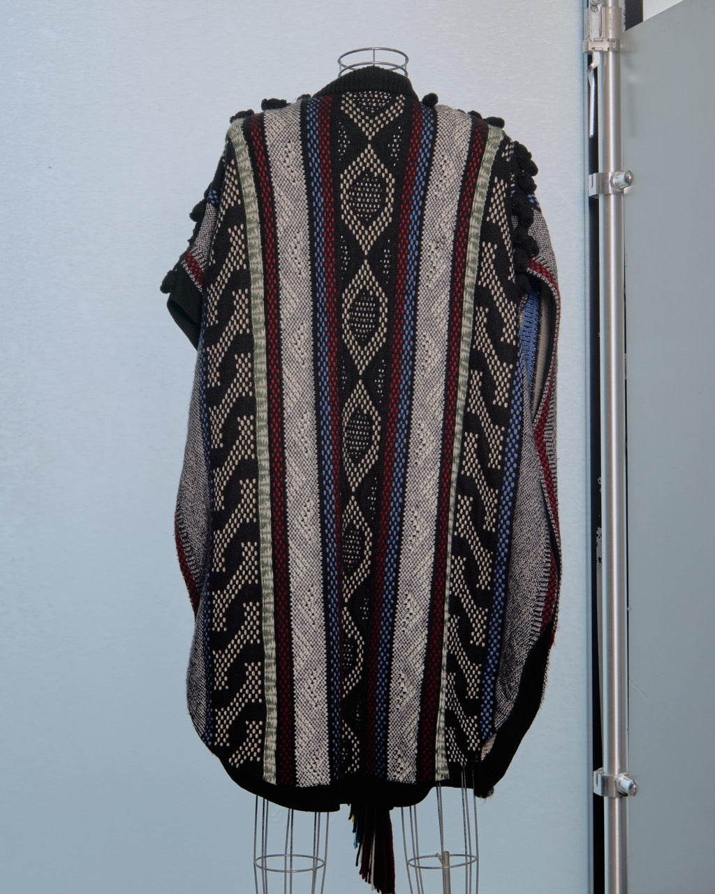 Patterned Chloe poncho on a mannequin against a light blue wall