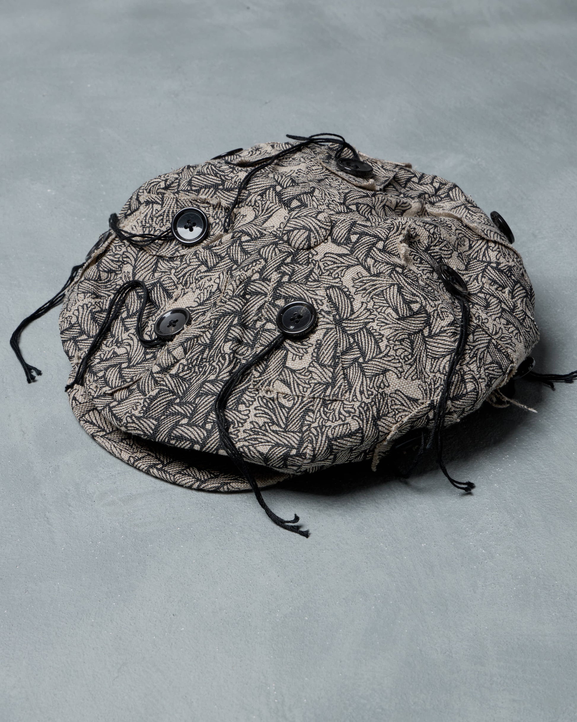 Round Christopher Nemeth hat black pattern on a gray background