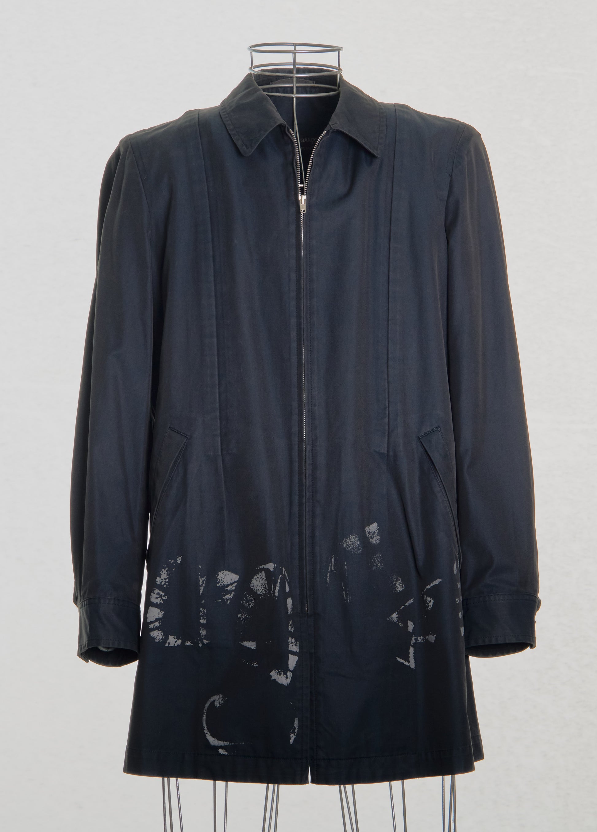 Dark blue Comme des Garcons raincoat with floral patterns on a white background