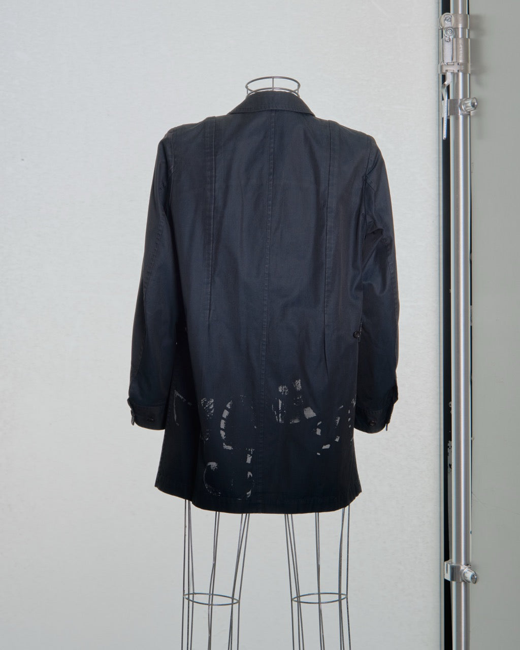 Black comme des garcons jacket on a mannequin against a plain background