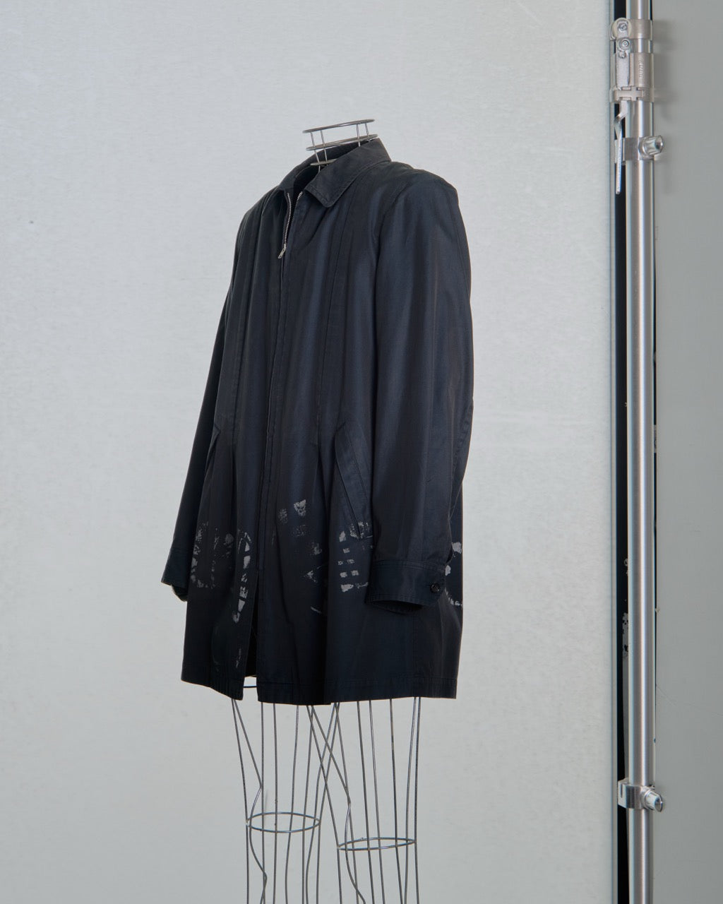 Black comme des garcons jacket on a mannequin against a plain background